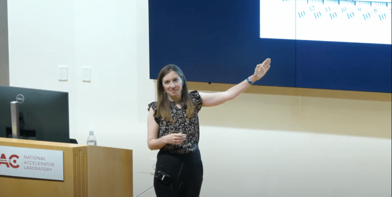 physicist Chelsea Bertram lectures in front of a blackboard about dark matter